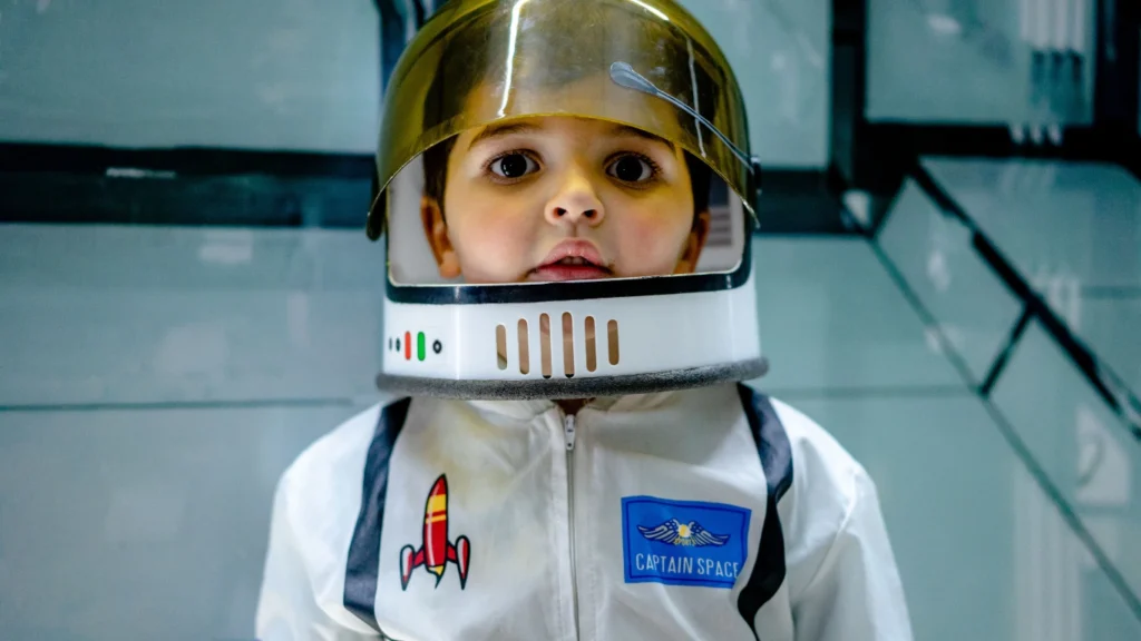 A young child wearing an astronaut helmet at the Kennedy Space Center